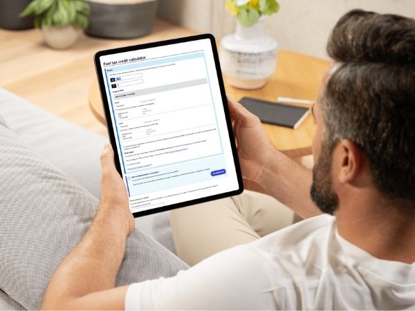 Man holding a tablet displaying the ATO Fuel Tax Credit Calculator, used to calculate eligible business fuel claims.